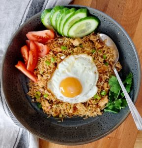 Nasi goreng served with eggs tomatoes and cucumbers